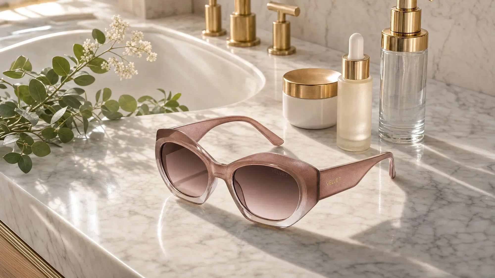 Velvet Eyewear® blush pink women's sunglasses beside skincare products, illustrating how sunglasses with 100% UV protection complement a daily beauty routine.