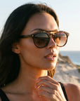 Amelia for Women by Velvet Eyewear. Best for Oval, Square, and Heart Face Shapes. All Seasonal Palettes. Worn by our model, Rocky standing on the edge of a cliff.